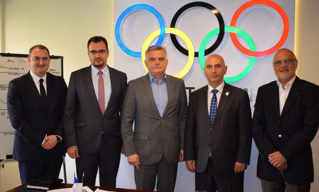 men posing for a picture in front of the olympic logo